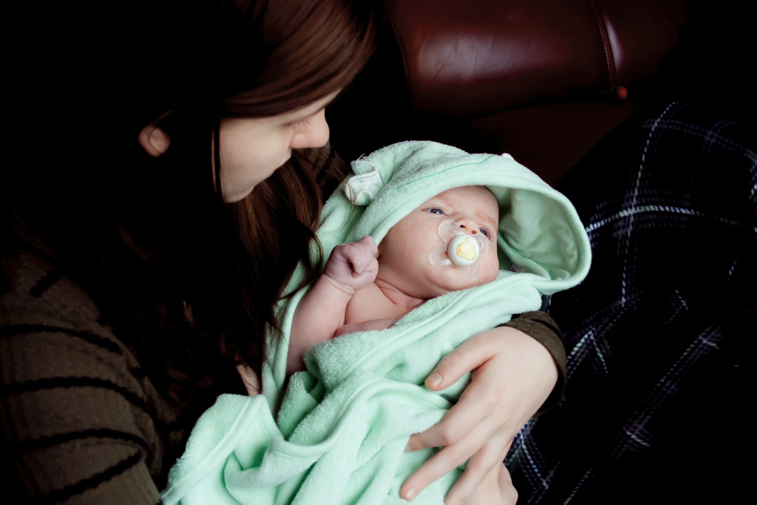 mum looking down at the baby she's holding wrapped in a green towel