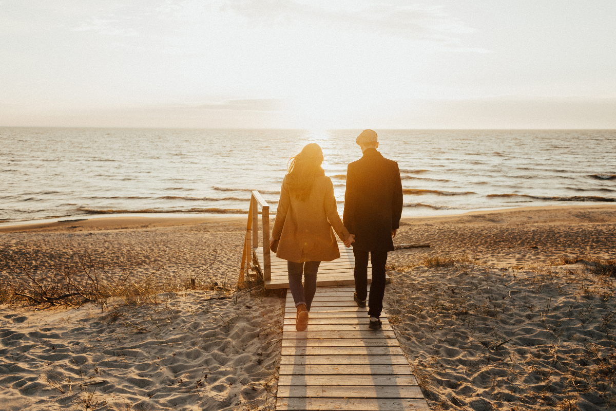 Couple walking on a path down to the beach